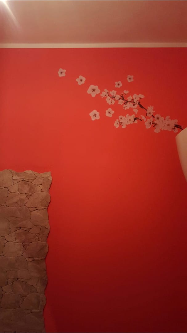 Parete rossa decorata con rami di ciliegio floreali realizzata da decoratori interni a Foligno